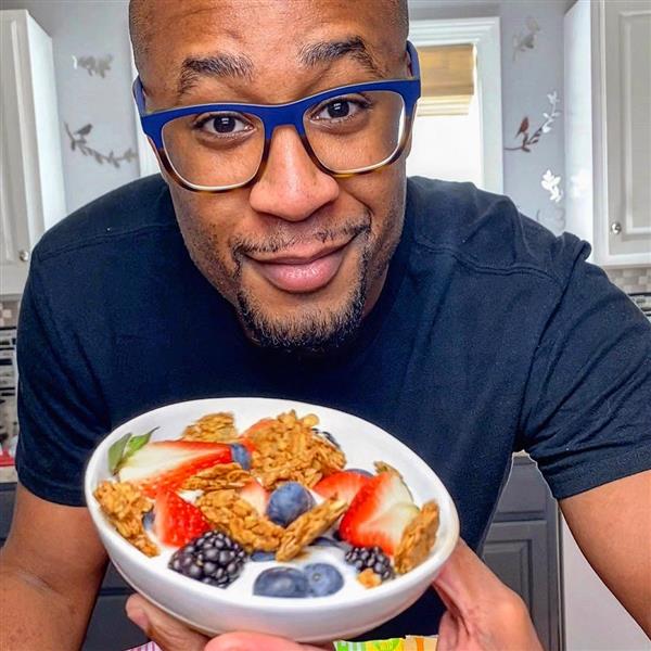  A close-up photo of Evan holding up a bowl of granola and fruit